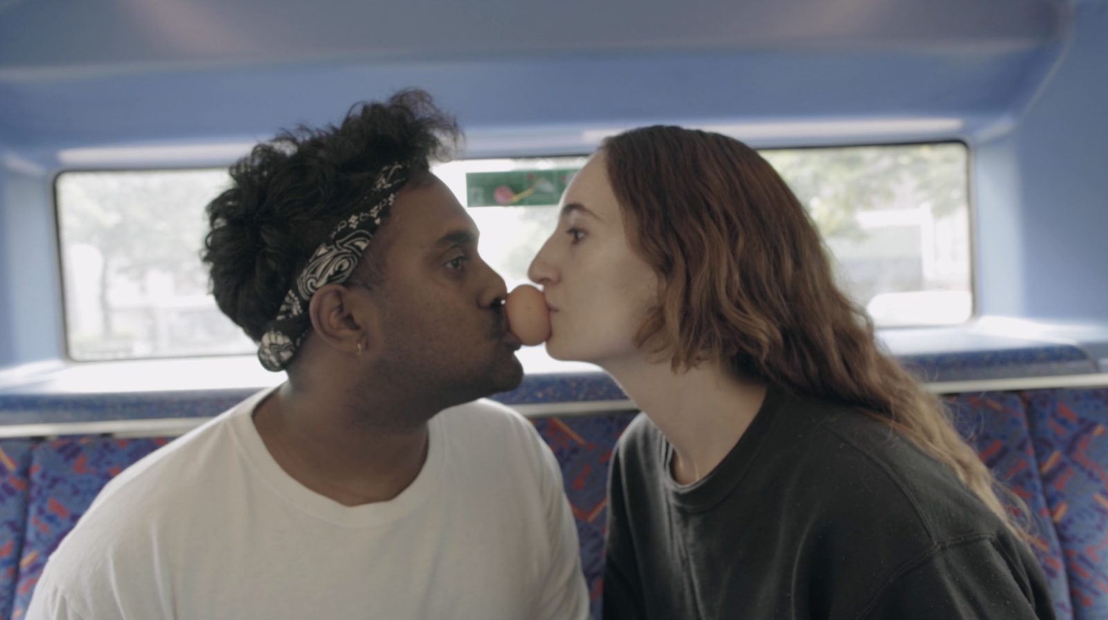 Hold On: two people hold an egg between their mouths on a London bus
